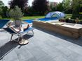 Une pierre élégante sur une terrasse moderne Femme se détend sur chaise longue sur terrasse en pierre calcaire Blaustein Azur avec vue sur piscine