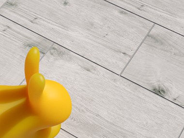 Les dalles imitation bois Amber Oak sur une terrasse, avec un lapin en caoutchouc jaune en tant que déco