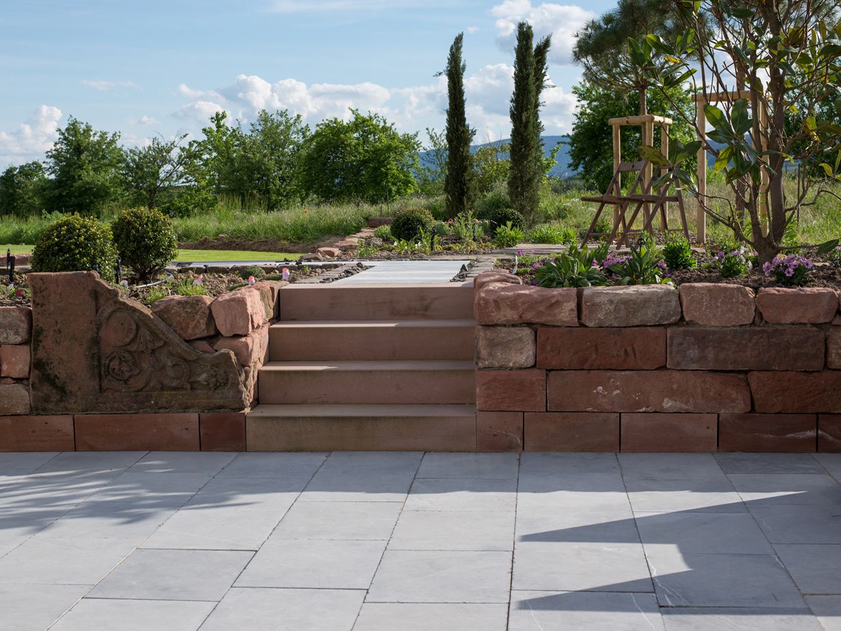 terrasse en pierre calcaire blaustein azur avec mur en pierre et jardin paysager