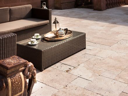 Un sofa de jardin avec une table basse où est servi du thé et un éléphant en accessoire sur le travertin Medium