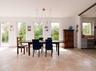 Heller Essbereich mit Holzmöbeln und Travertinfliesen in Beige als Bodenbelag