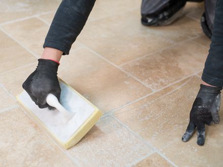 Fliesenleger reinigt den Travertinboden nach der Verlegung